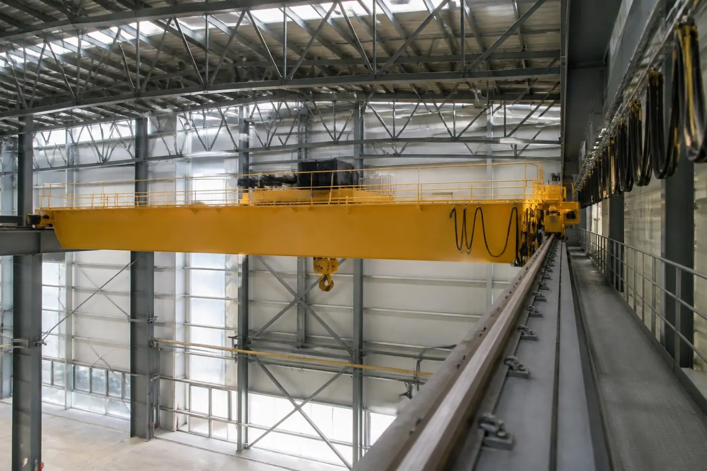 Electrician in a fall-arrest harness installing a new variable frequency drive control panel on an overhead crane bridge walkway during a modernization outage