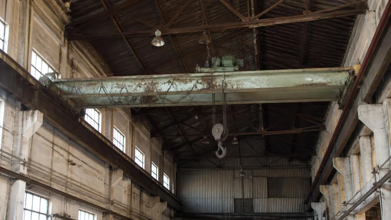 Old aging overhead crane compared side by side with a brand new modern crane in a factory